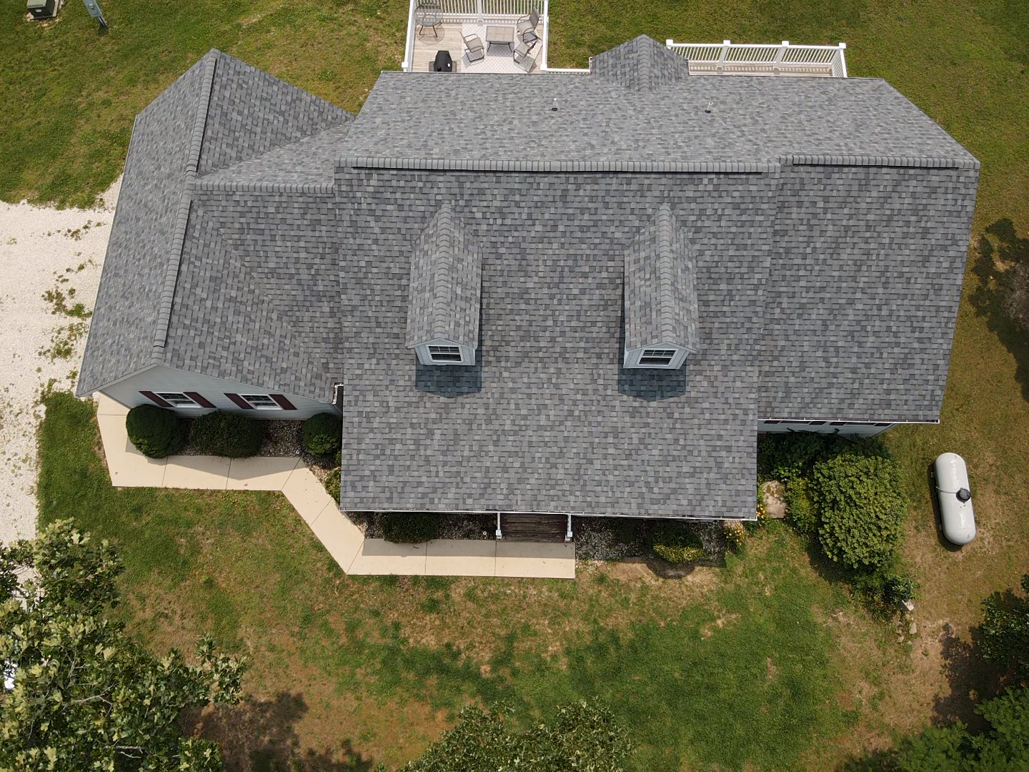 Overhead view of a house with a gray shingled roof, red roof section, and grassy yard.