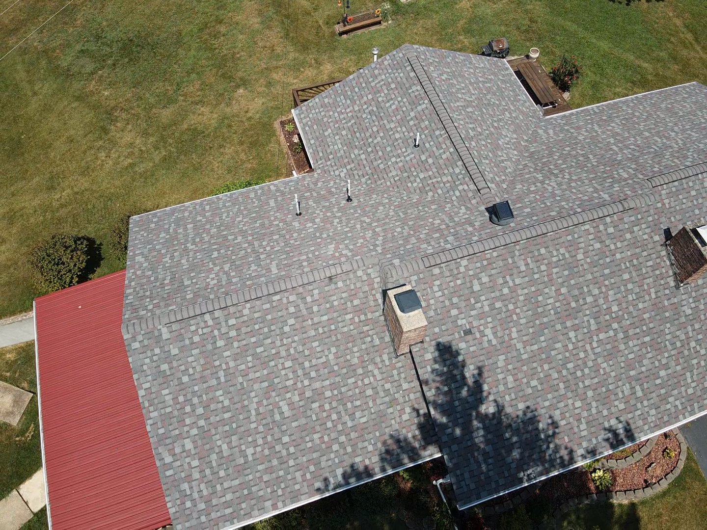 Overhead view of a house with a gray shingle roof and a red roof section.