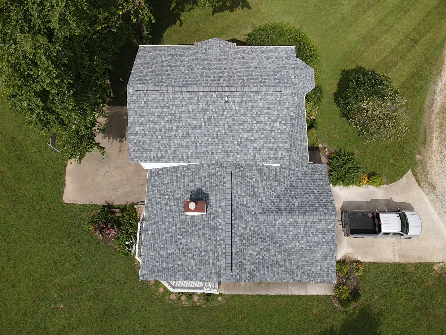 Overhead view of house with gray roof, chimney, driveway, green lawn, and parked truck.