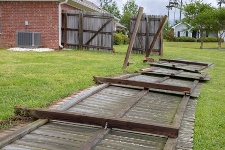 A wood privacy fence damaged as a result of a storm