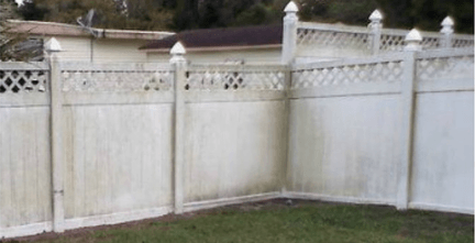 A dirty vinyl fence covered in algae and mildew