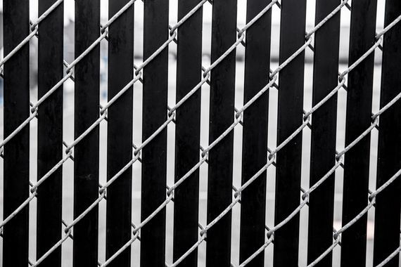 Black vinyl slats inserted into a galvanized steel chain-link fence and a close-up view of newly installed chain-link fencing mesh.
