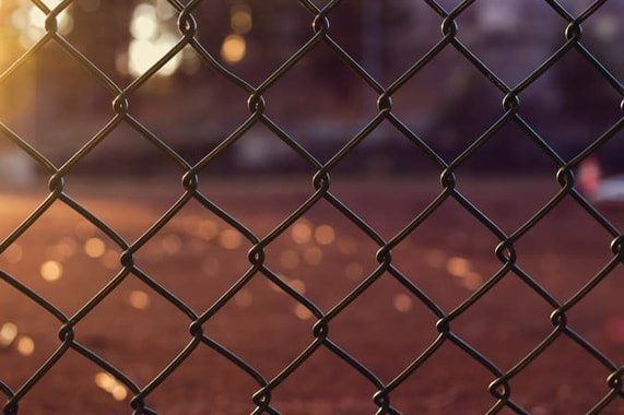 a close up of a chain link fence at sunset