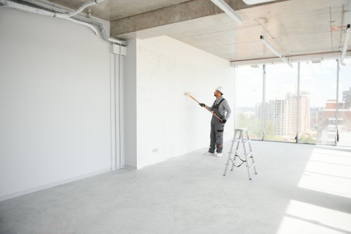 A man is painting a wall in an empty room.