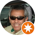a man wearing sunglasses is sitting in a car and smiling for google reviews profile