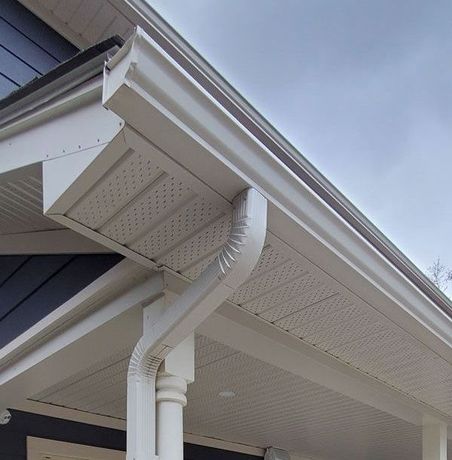 a close up of a white eaves trough and downspout on a porch of a house