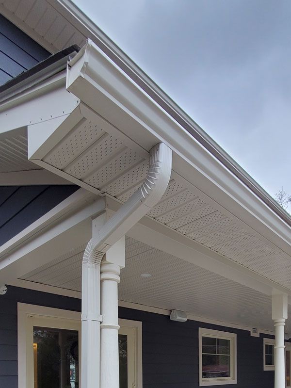 a blue house with a white porch and a white eaves trough and downspout
