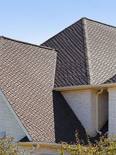 the roof of a white brick house with a brown asphalt shingle roof