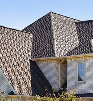 a white brick house with a black asphalt shingle roof and windows