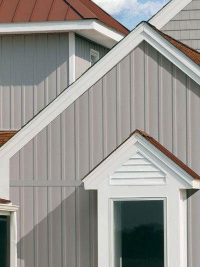 a close up of a house with gray siding and a red shingle roof