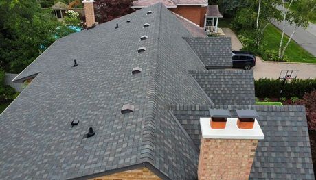 an aerial view of a house with an asphalt shingle roof and chimneys