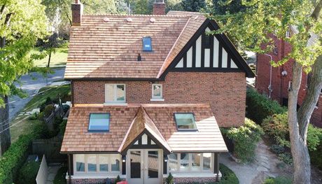 an aerial view of a brick house with a cedar roof
