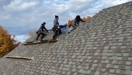 a group of experts working on an asphalt shingle roof