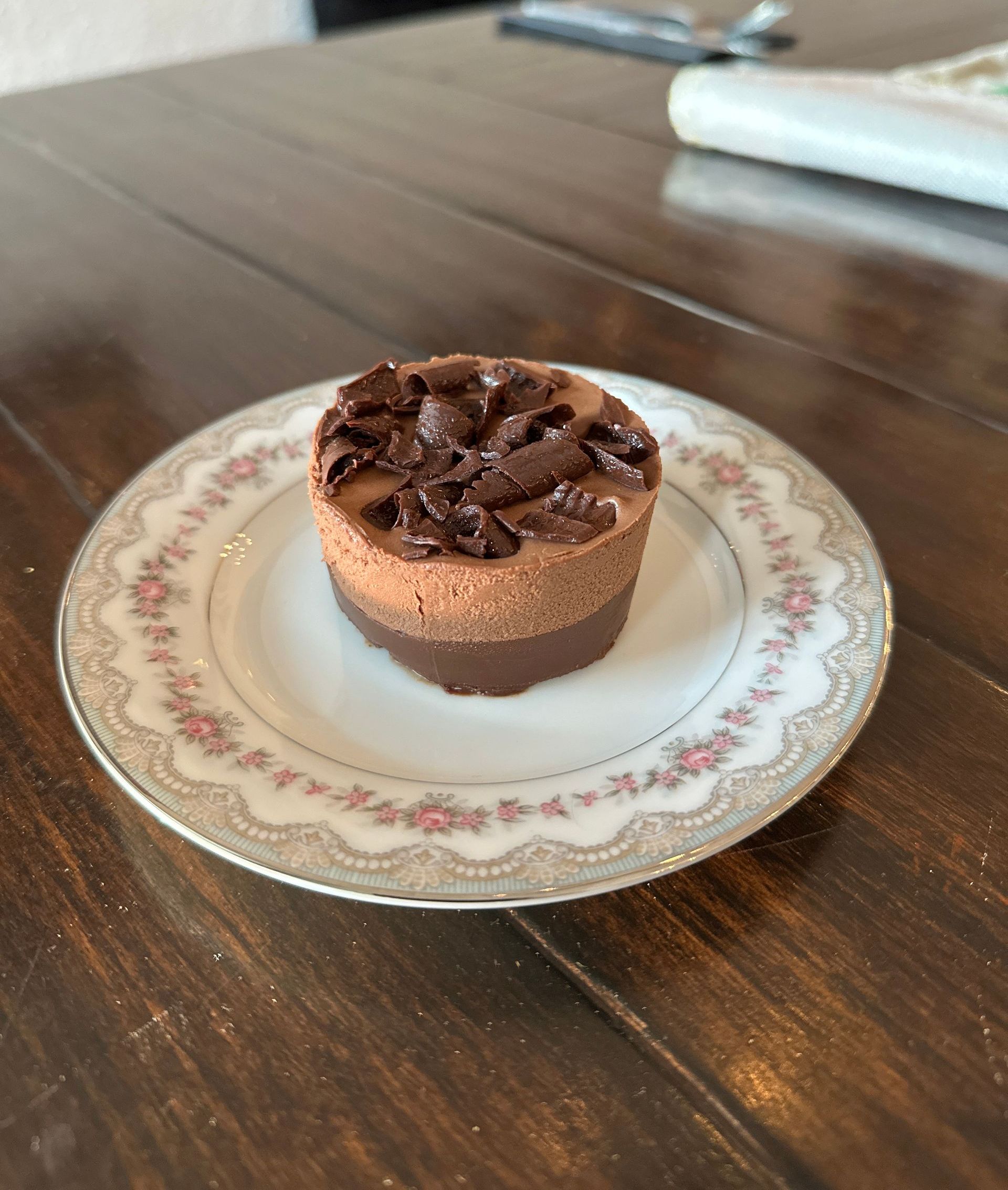 A small chocolate cake on a plate on a wooden table.