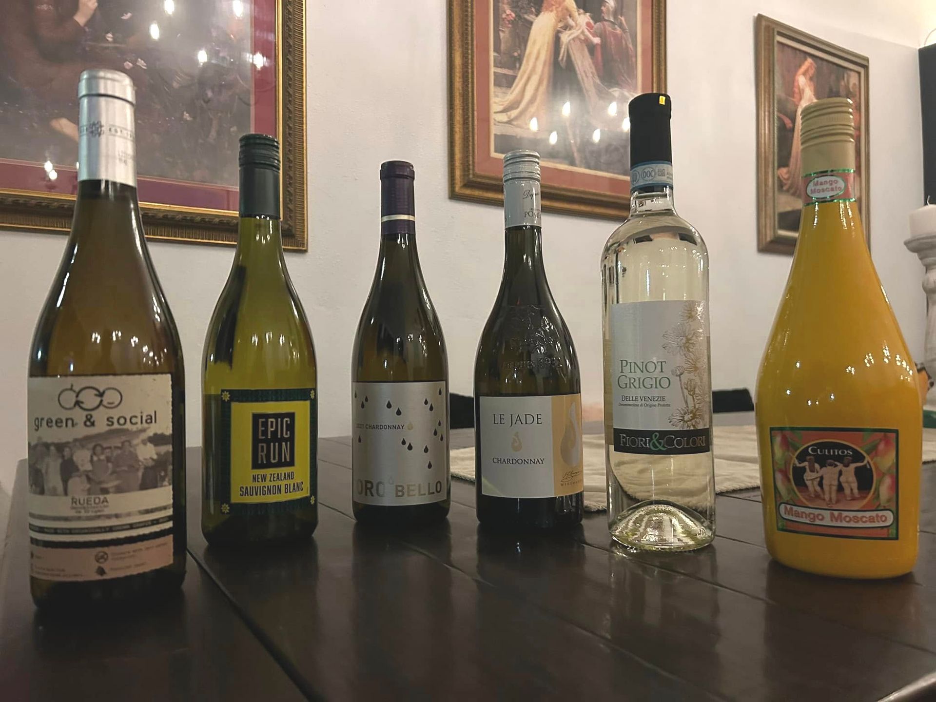 Five bottles of wine are lined up on a wooden table