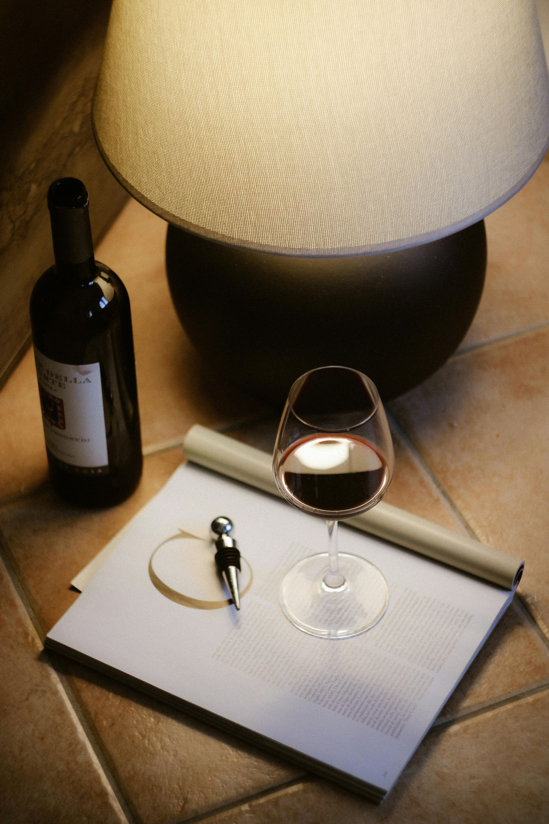 A bottle of wine sits next to a glass of wine