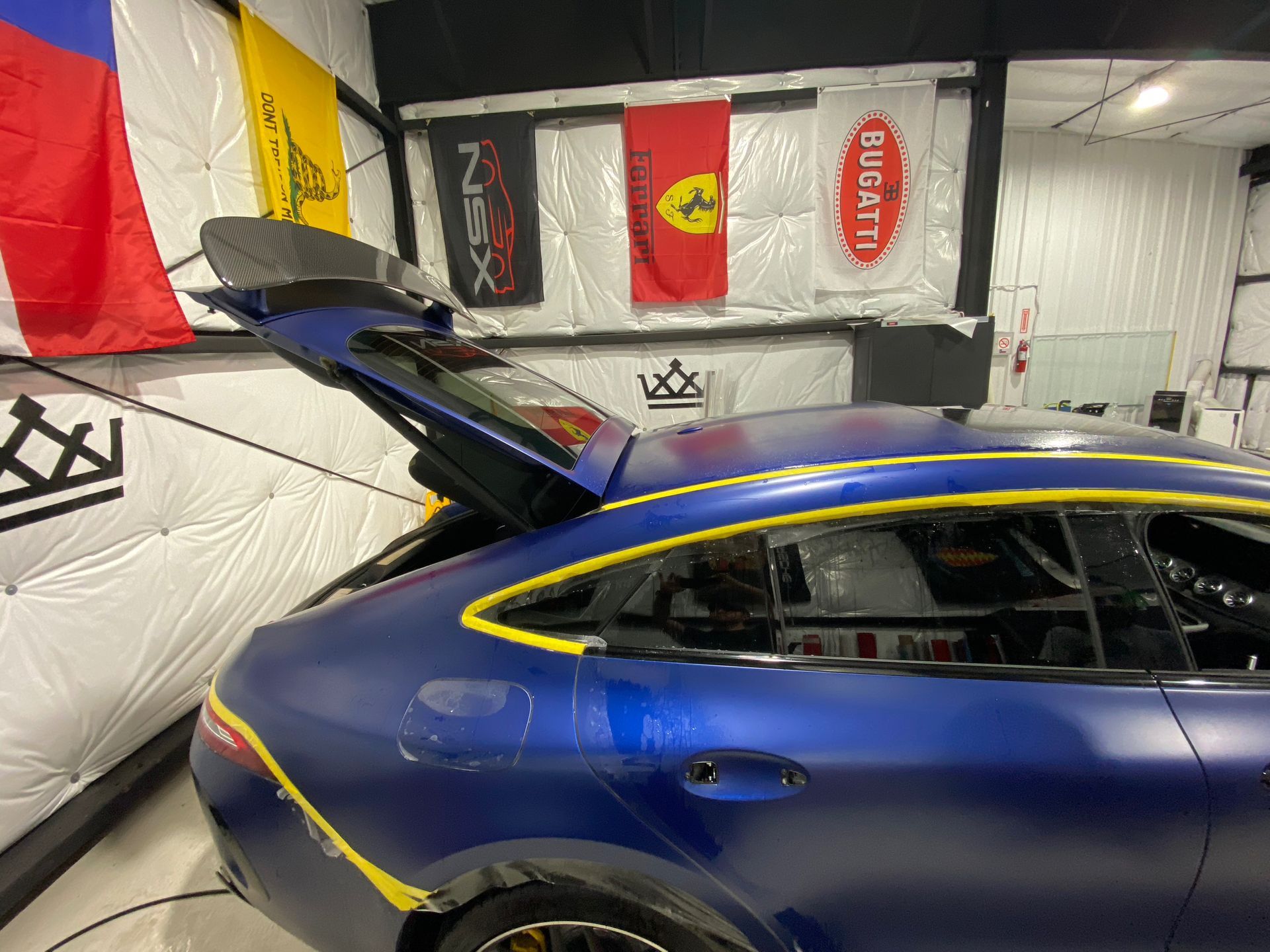 A blue sports car is parked in a garage with its trunk open.
