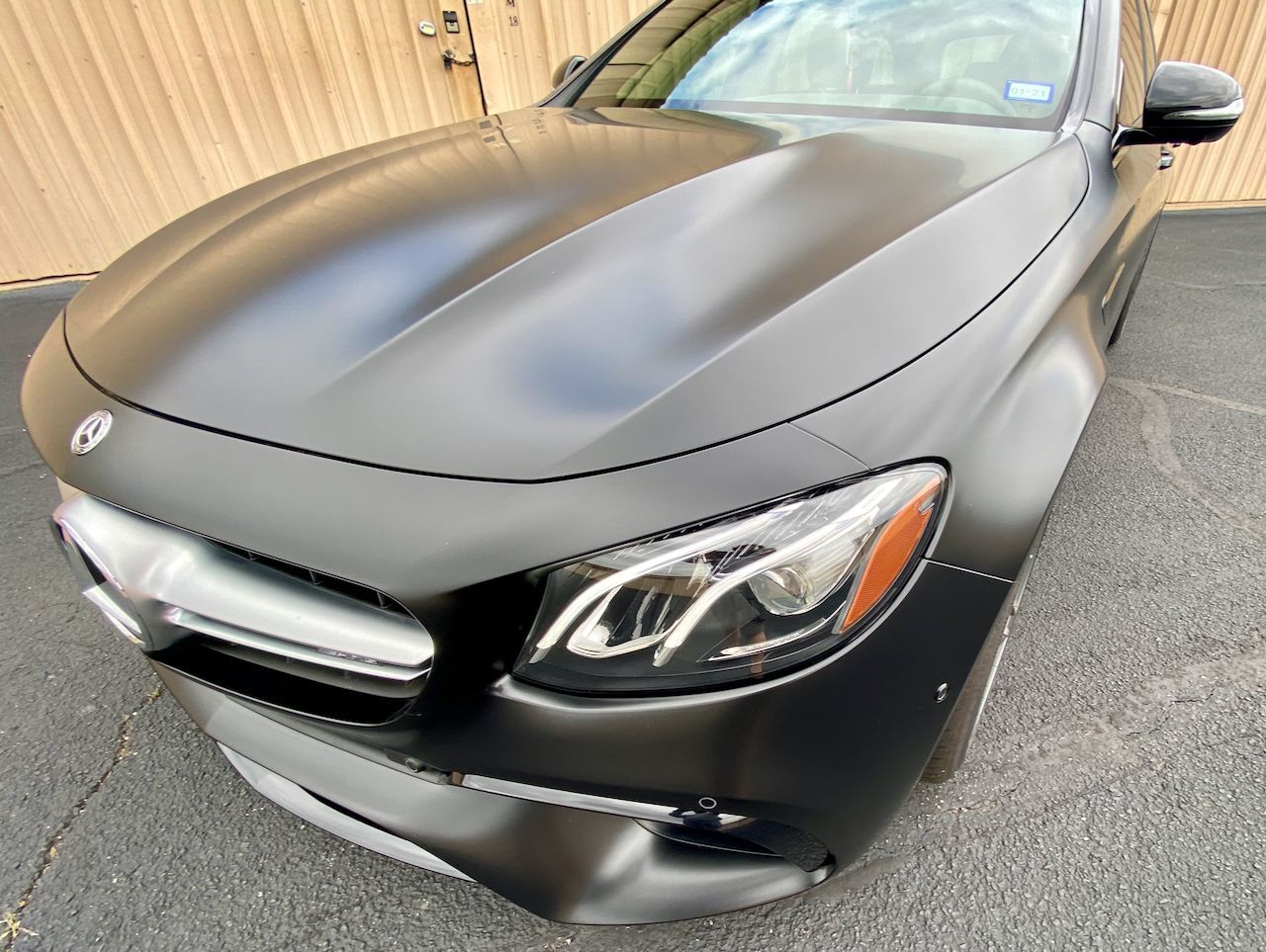 Black Mercedes-Benz car with matte finish, parked outside a building.