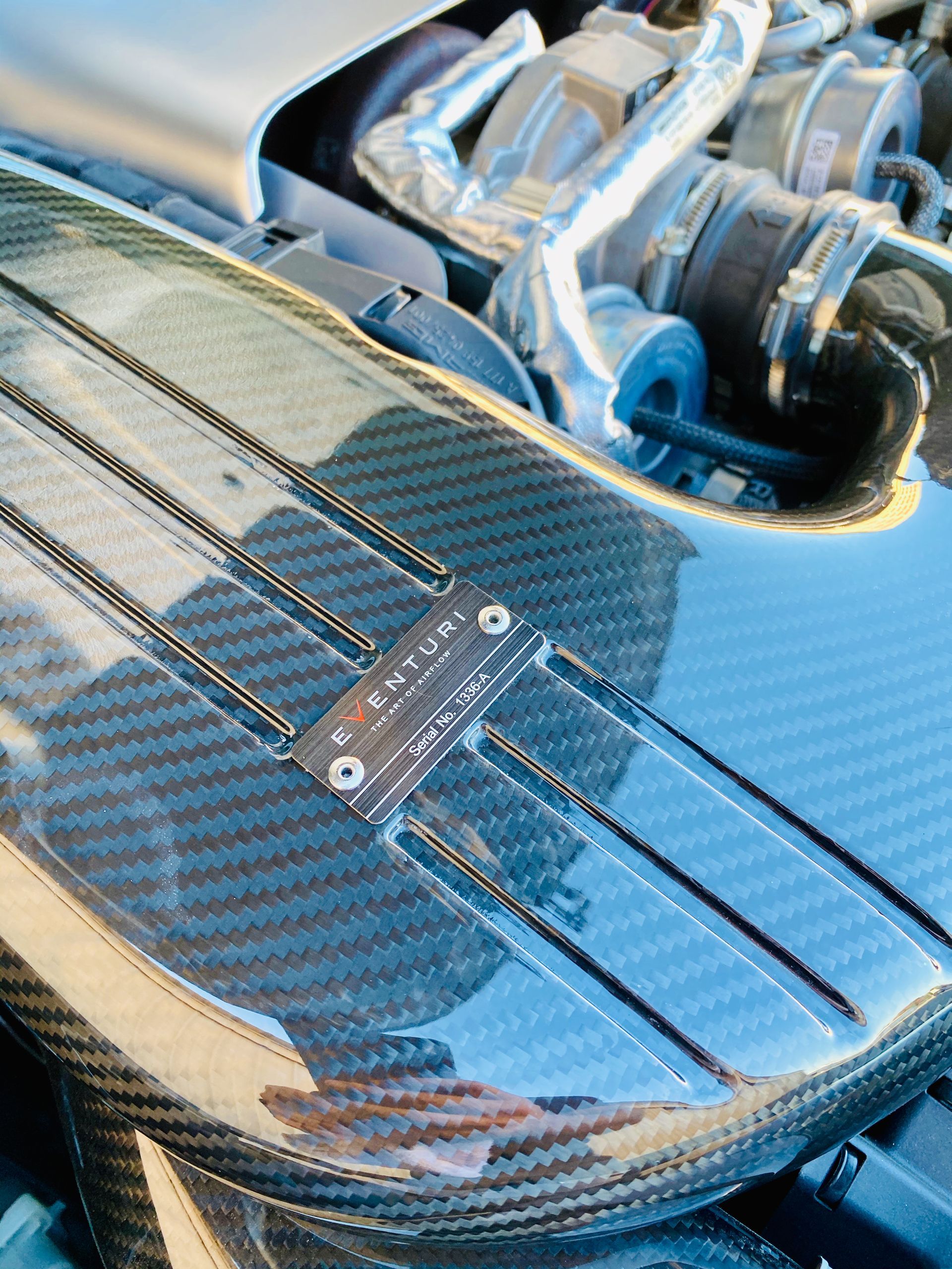 A close up of a carbon fiber hood of a car.