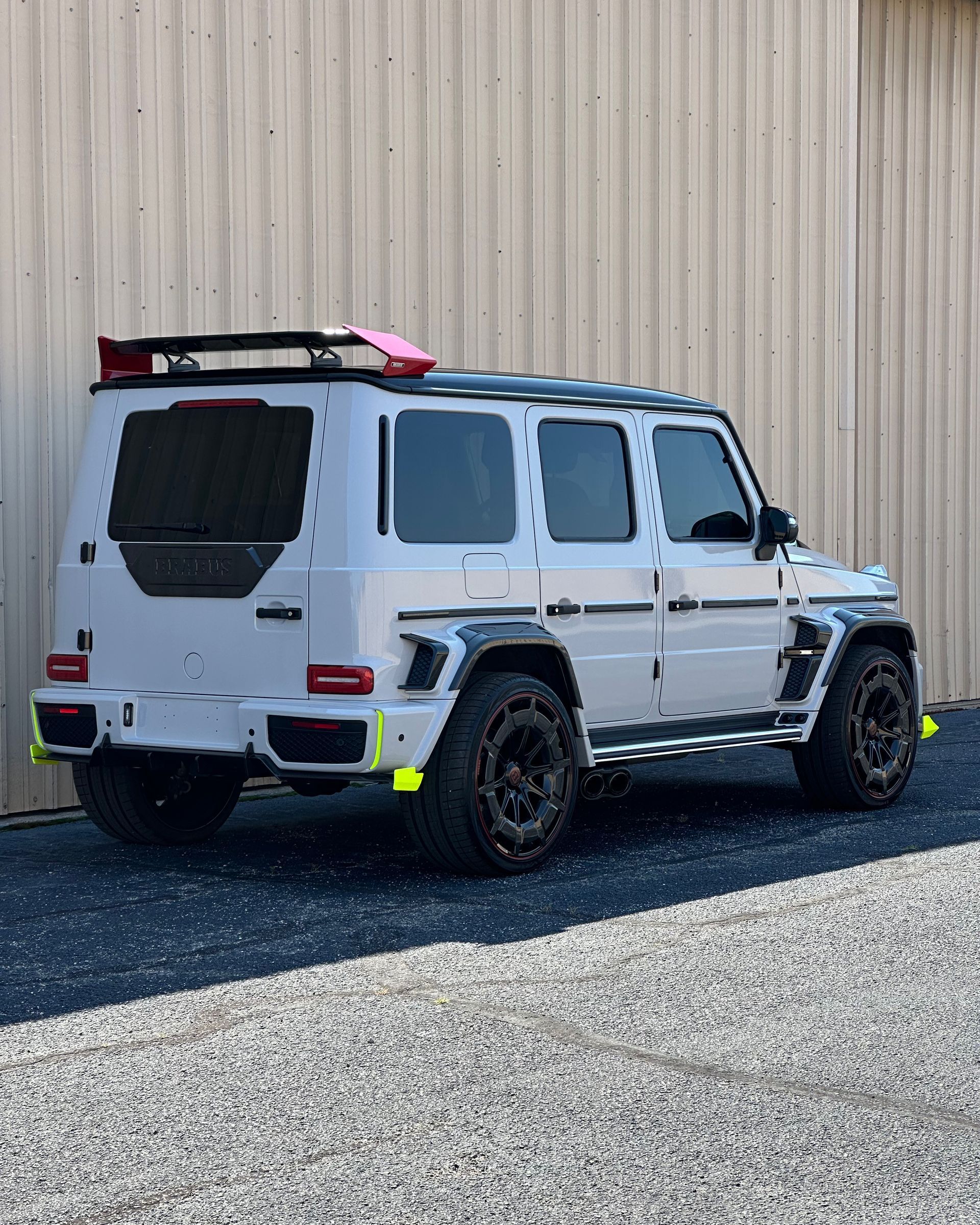 Gray Mercedes G-Wagon with black rims, black roof rack, and neon yellow accents parked outside.