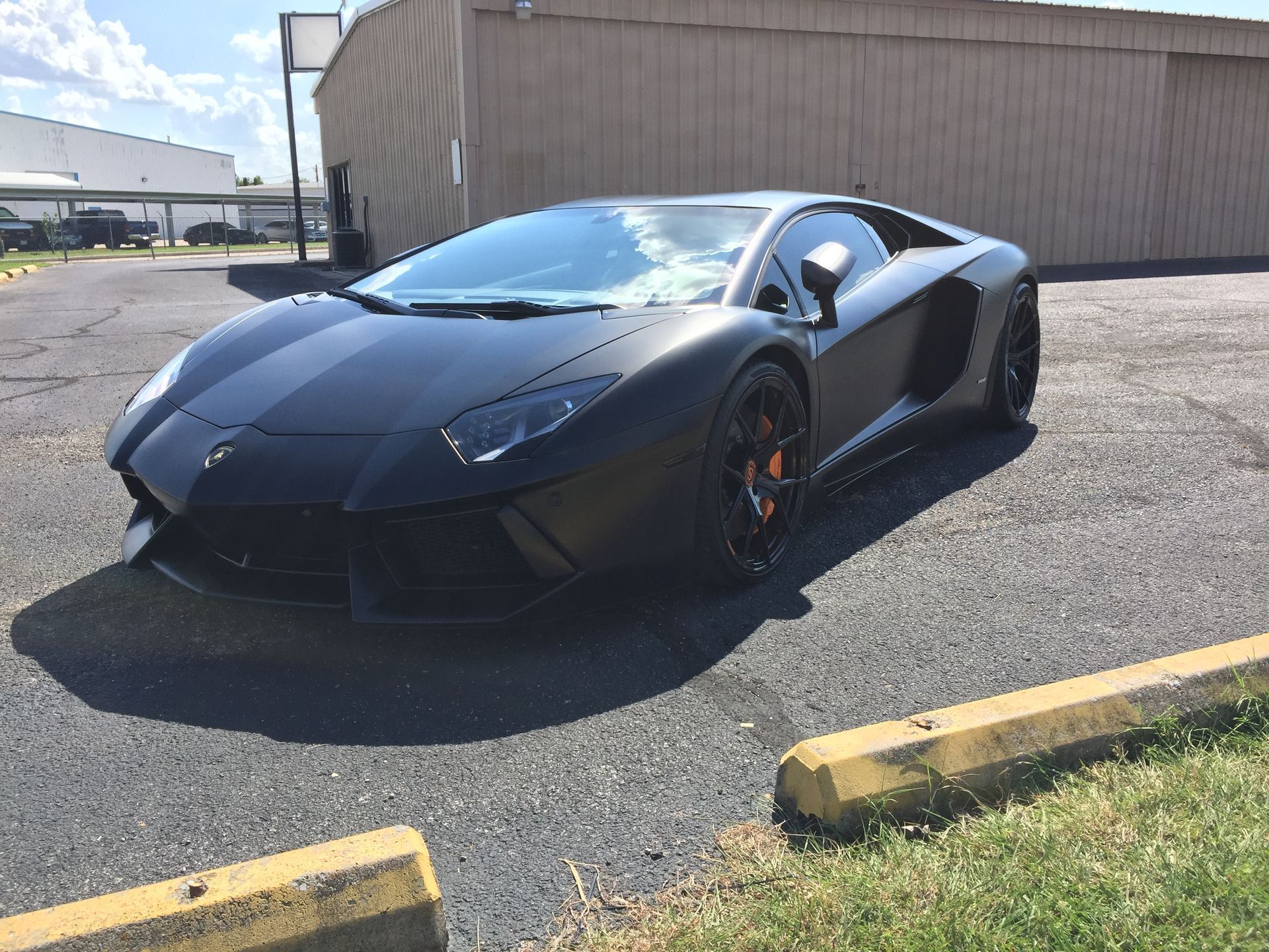 A black lamborghini aventador is parked in a parking lot.