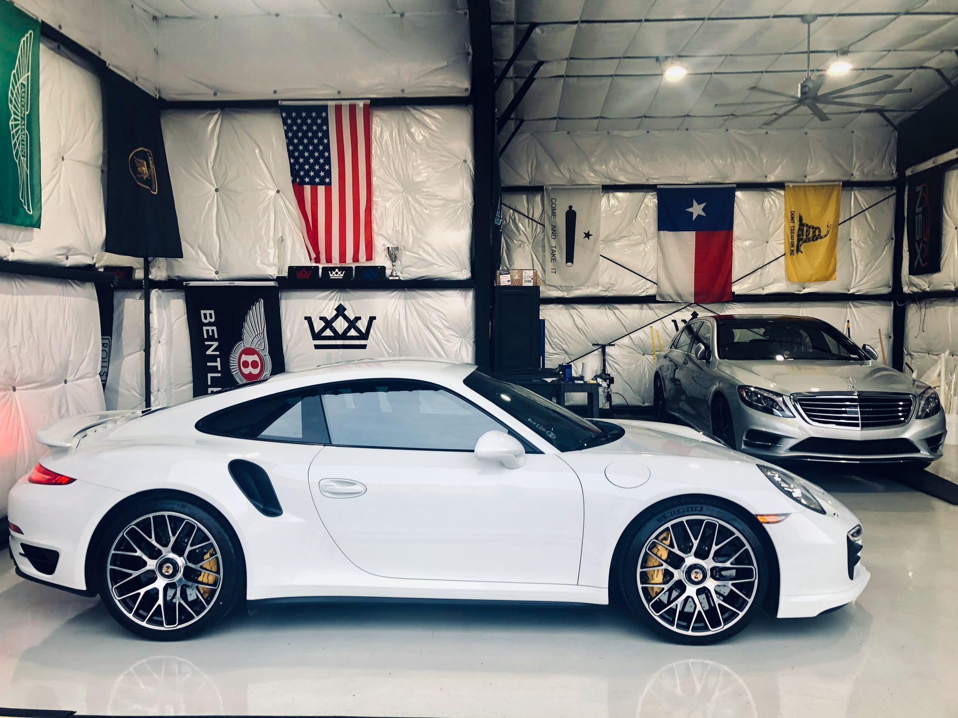 A white porsche turbo is parked in a garage