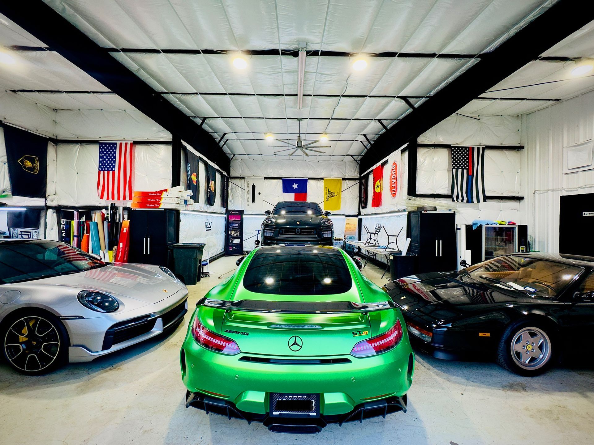 A green sports car is parked in a garage surrounded by other cars.