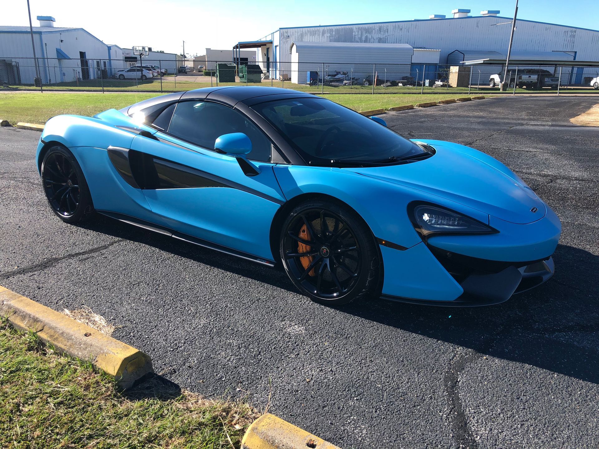 A blue sports car is parked in a parking lot.