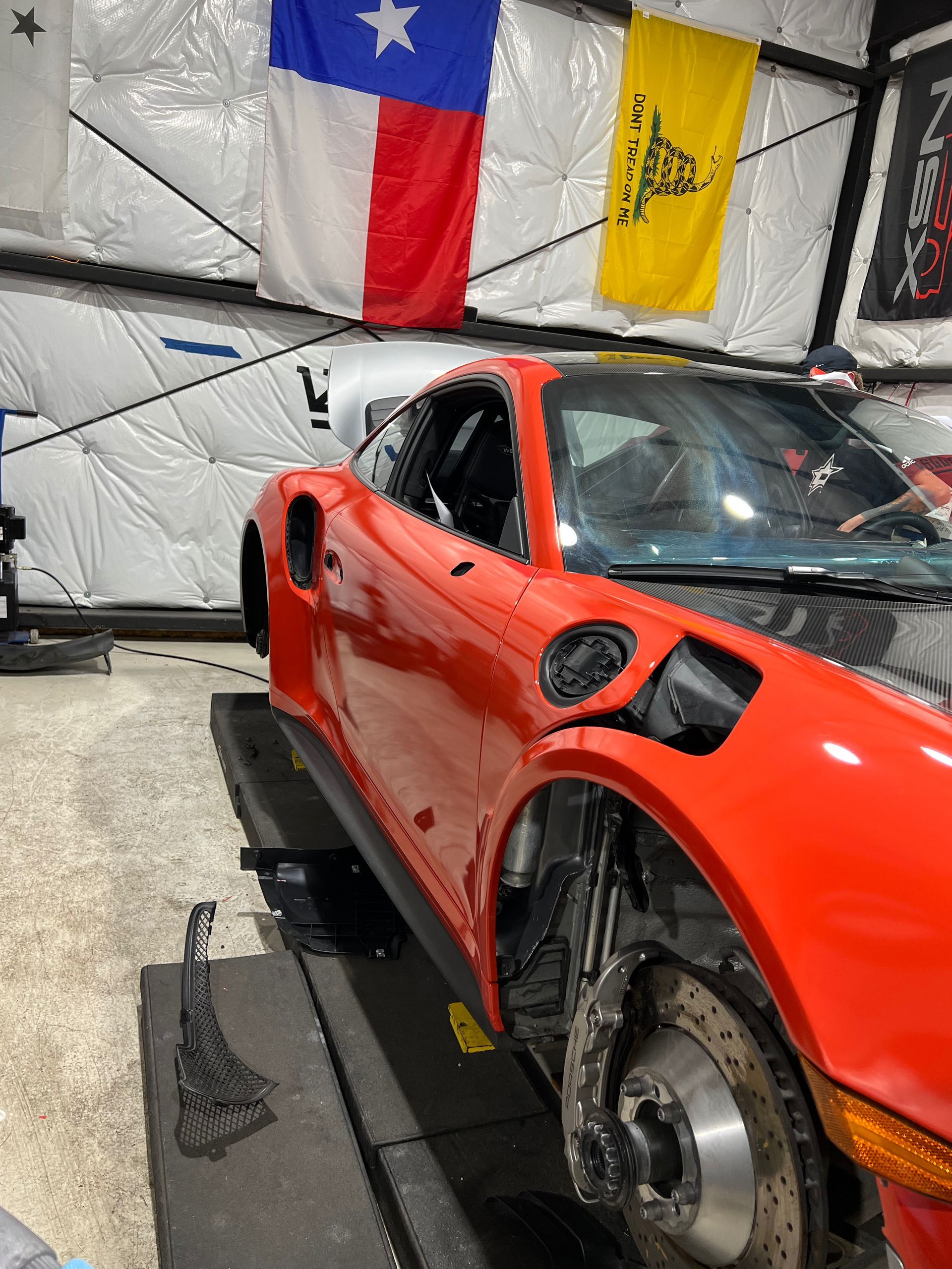 Red sports car on a lift in a garage with a Texas flag.