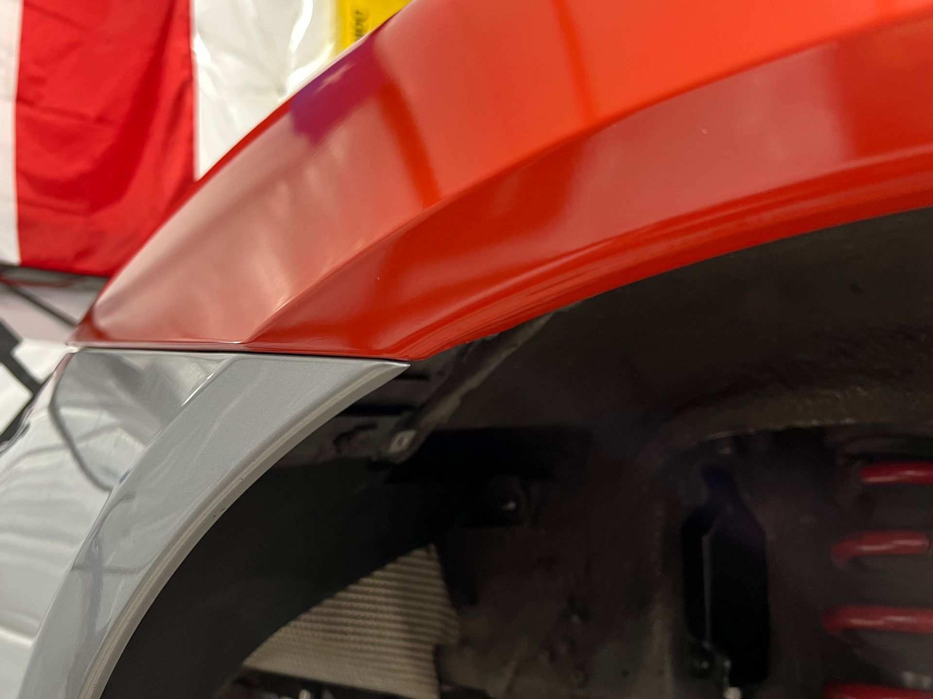 Red car fender over a silver wheel well, close up.