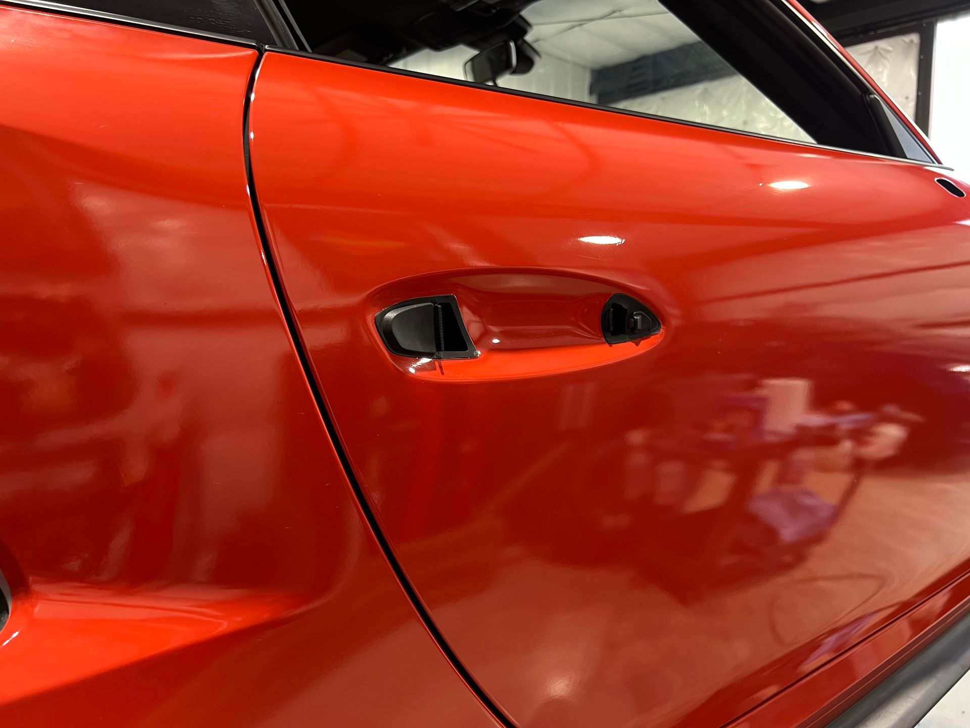 Red car door with a black handle, shiny surface.