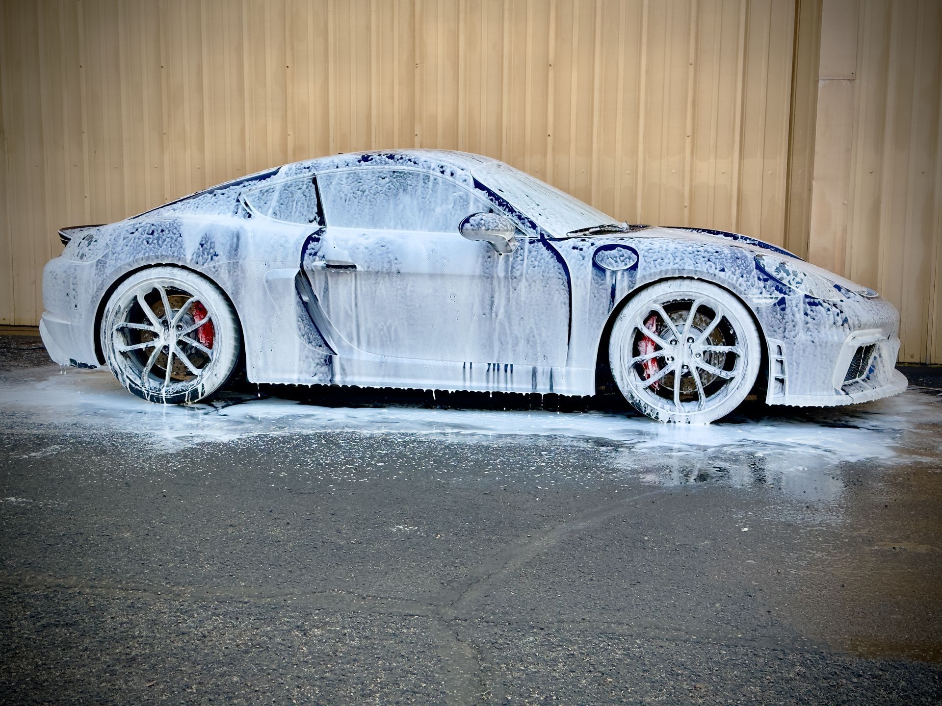 A car covered in foam is parked in front of a building.