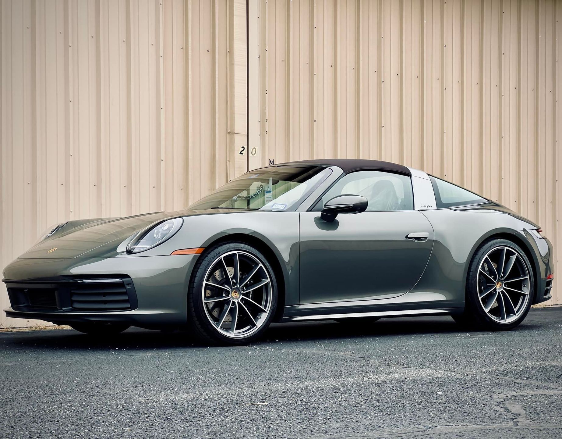 Gray Porsche 911 Targa parked in front of a tan building.