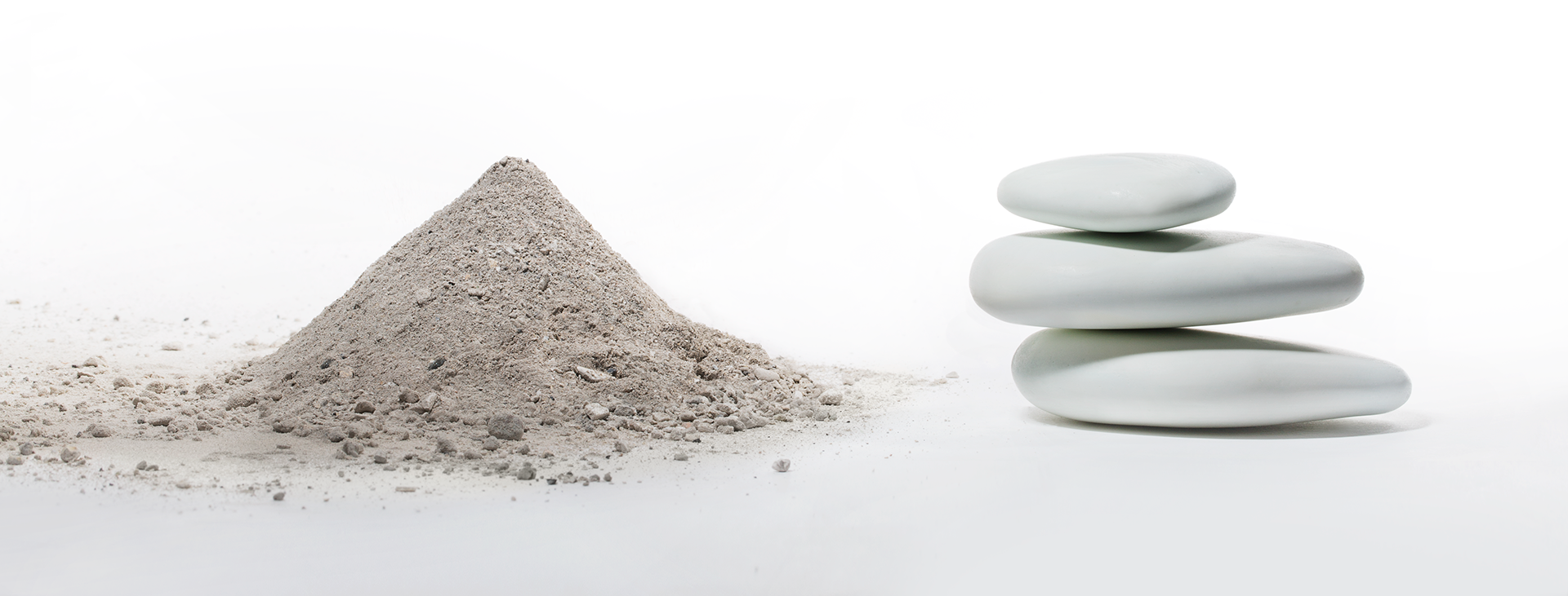 There is a pile of sand next to a pile of rocks stacked on top of each other.