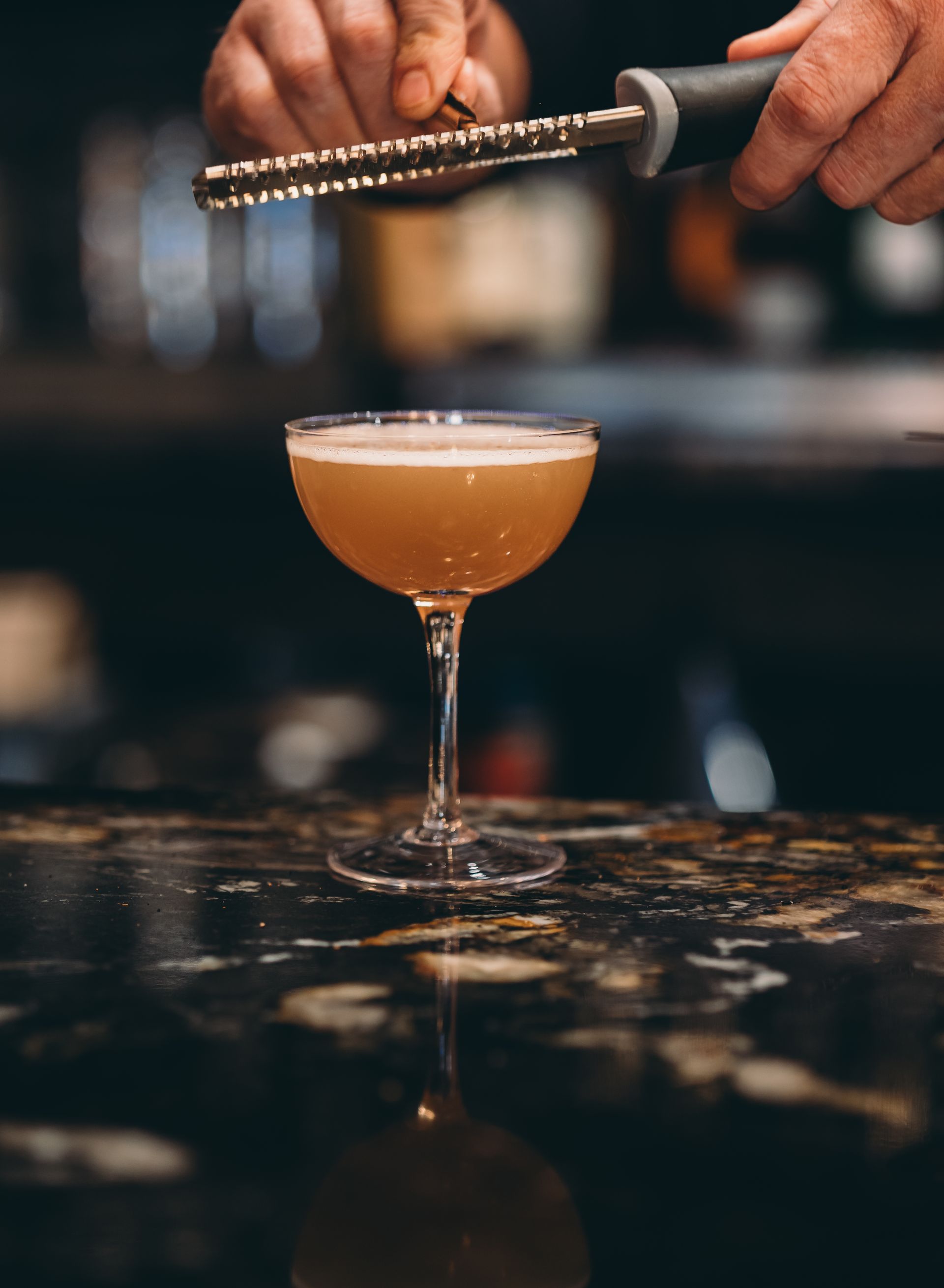 A bartender is preparing a cocktail in a martini glass.