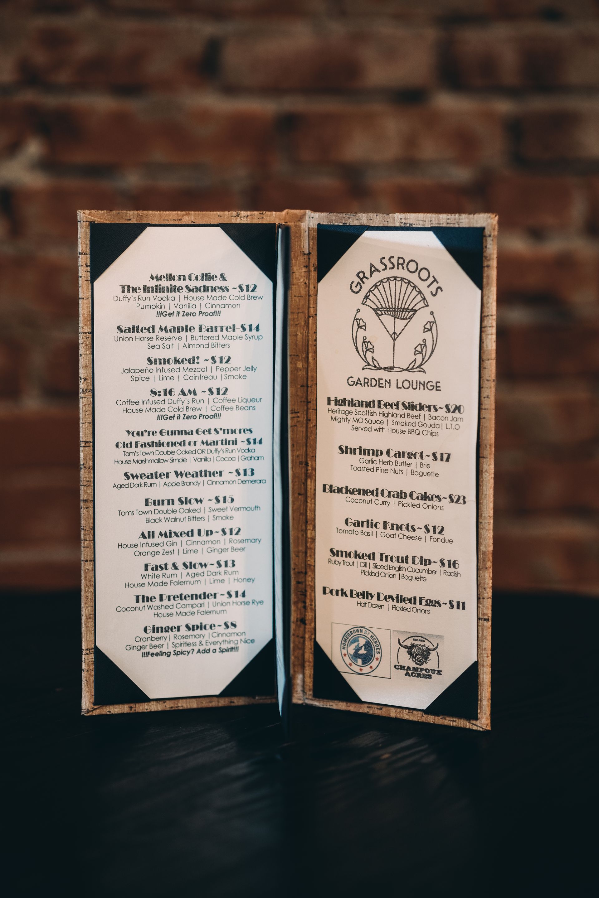 A menu is sitting on a table in front of a brick wall.