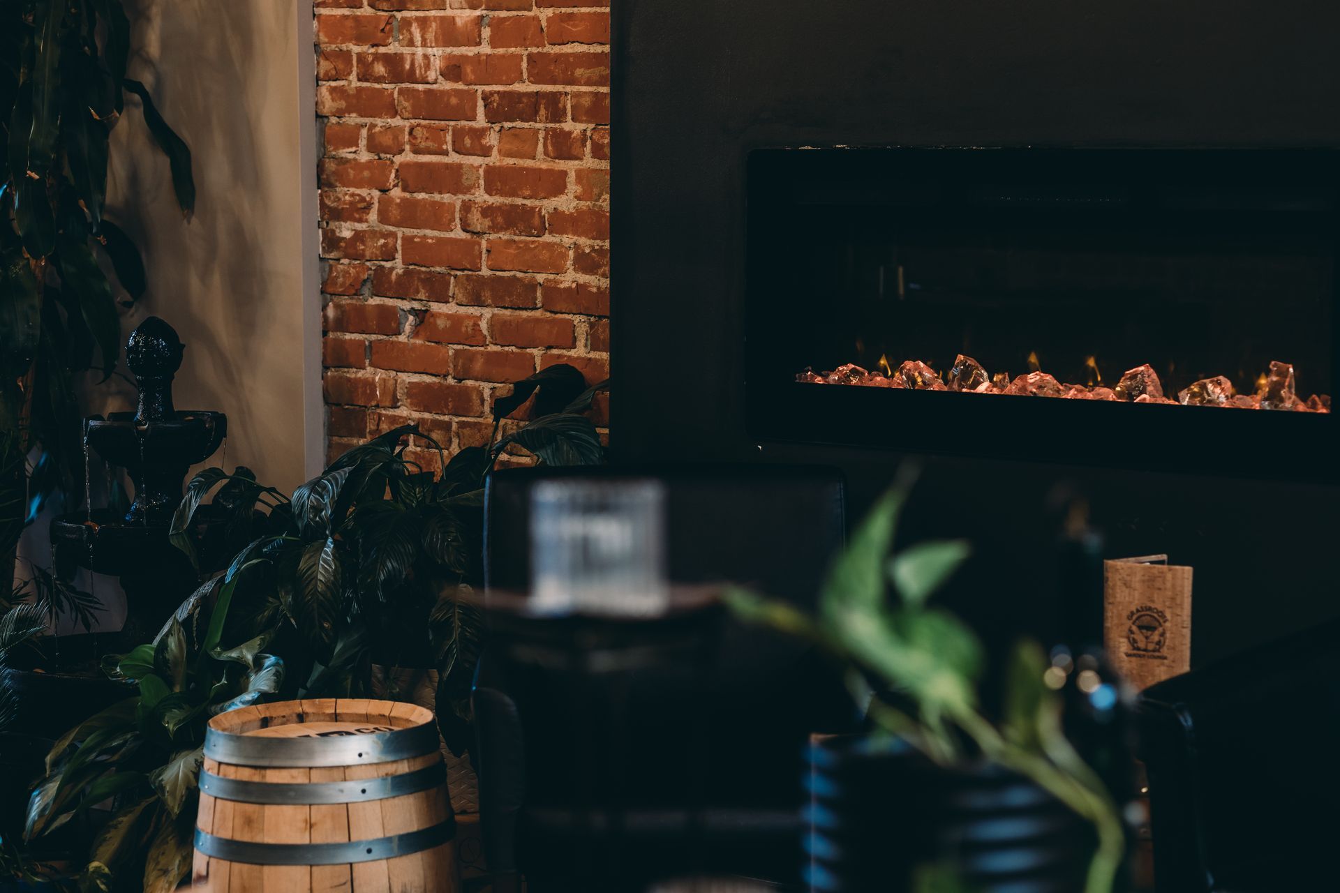 A wooden barrel is sitting in front of a fireplace in a room with a brick wall.