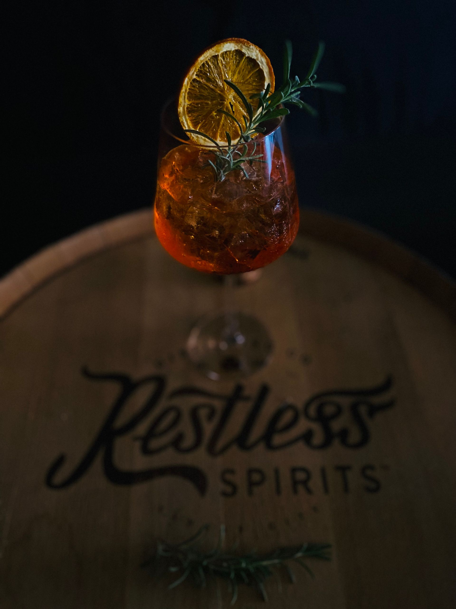 A glass of restless spirits sits on a wooden barrel