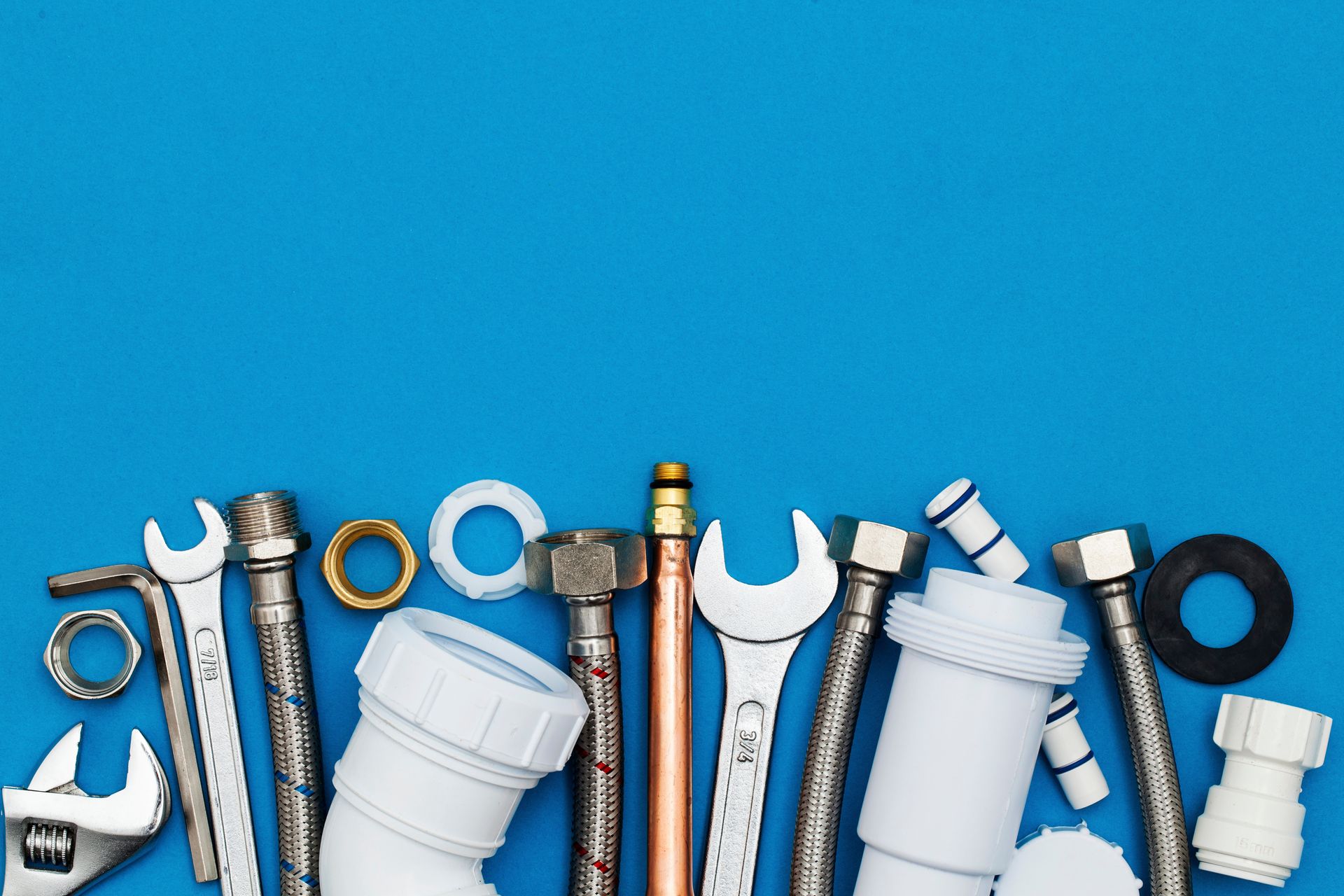 Plumbing tools and fittings laid in a row on a blue background.