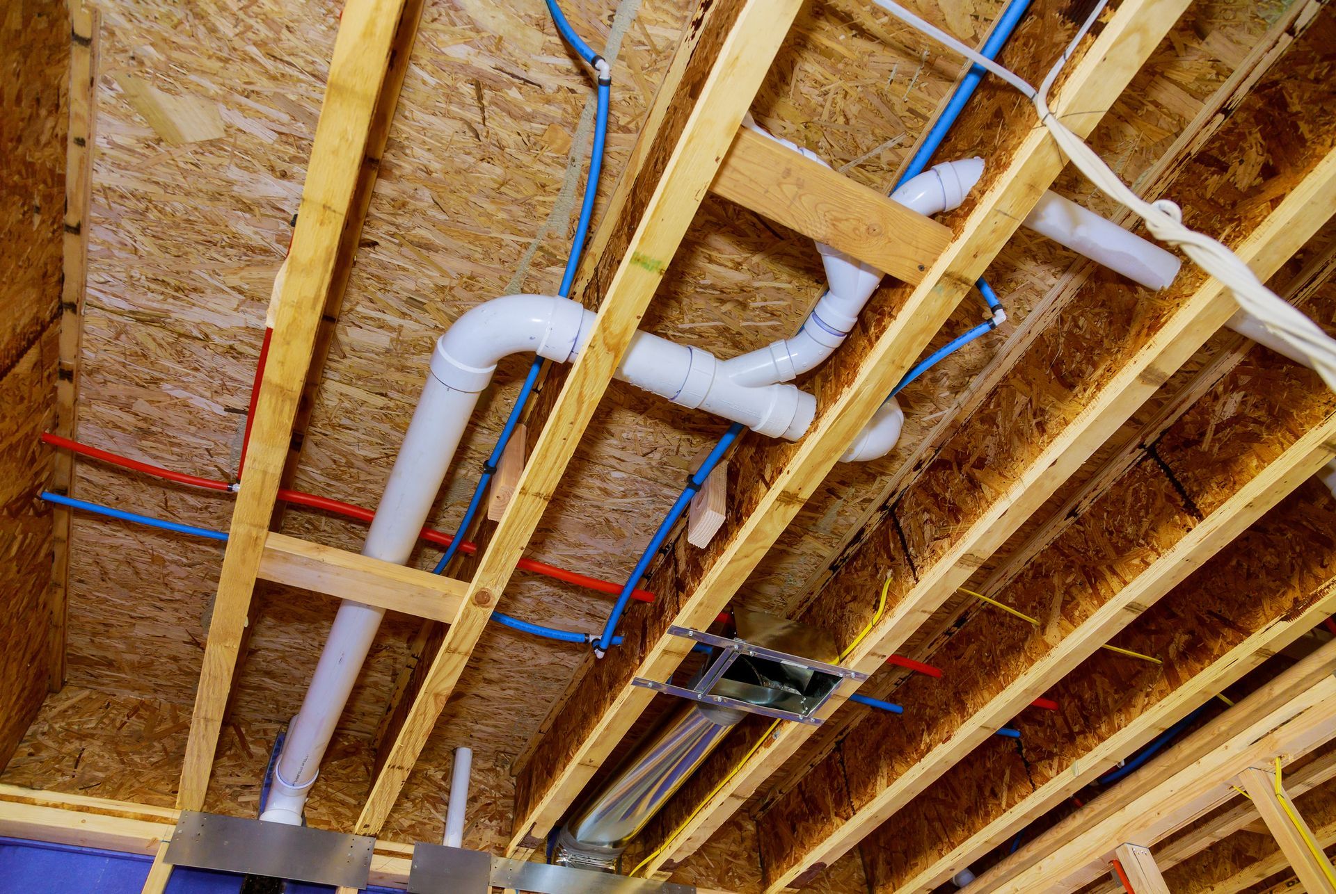 The ceiling of a house under construction with pipes coming out of it.