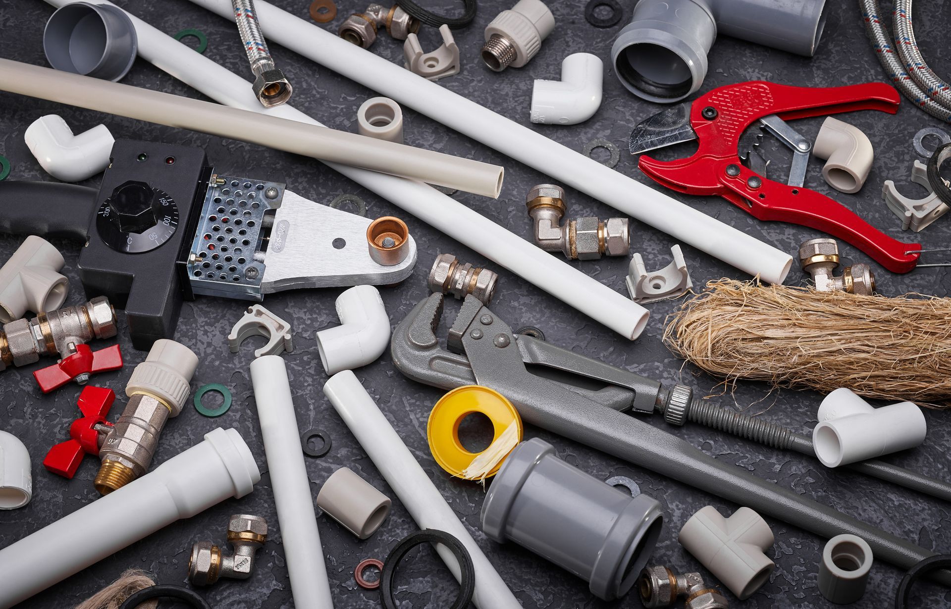 Plumbing tools and PVC pipe fittings arranged for repair installation and plumbing projects.