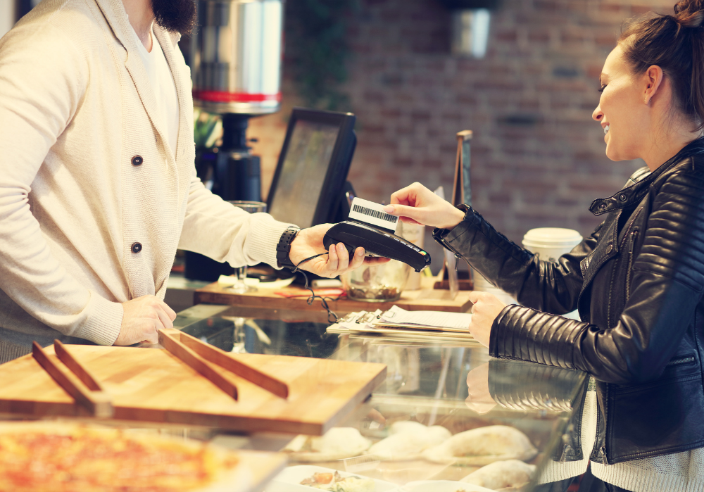 A woman is paying with a credit card in a bakery.