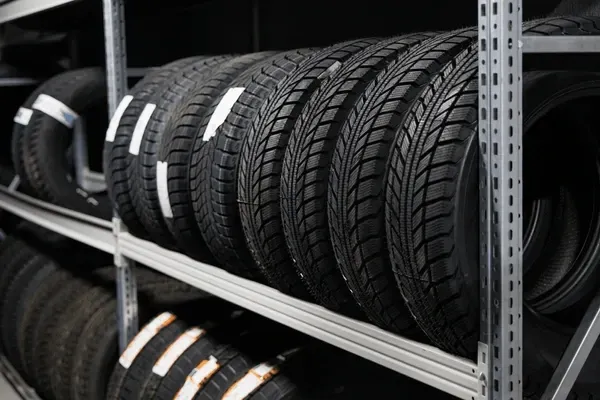 Tires stored on metal shelves in a garage or auto shop, ready for sale or service.