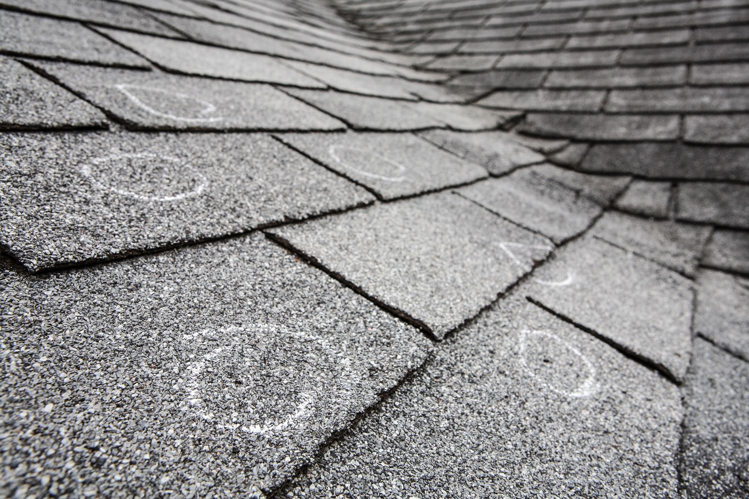 A black and white photo of a roof with hail damage.
