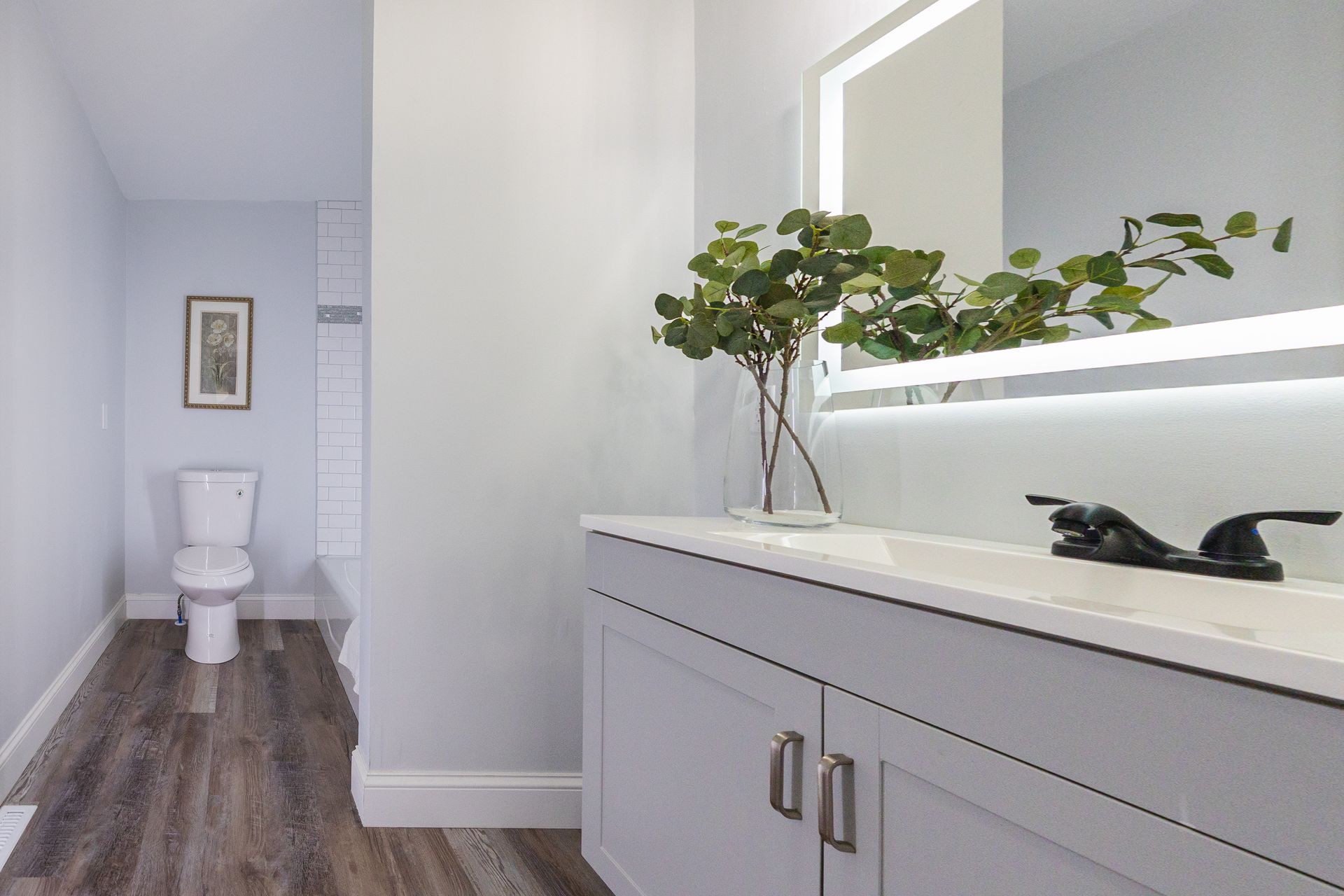 A bathroom with a toilet , sink and mirror.