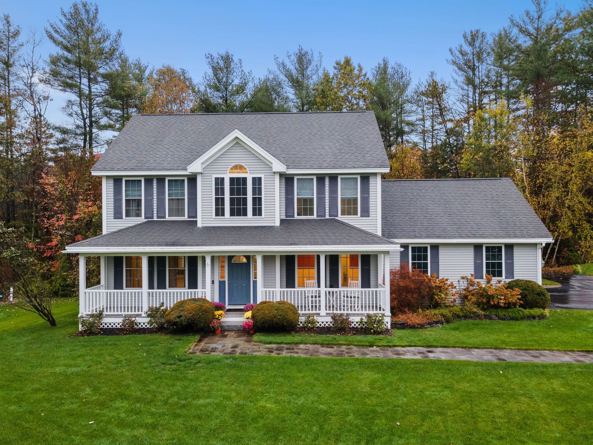 A large white house with a gray roof and a large porch