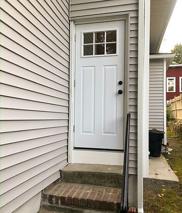 A white door with a window is on the side of a house