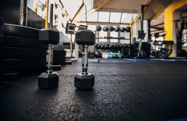 Two dumbbells are sitting on the floor of a gym.
