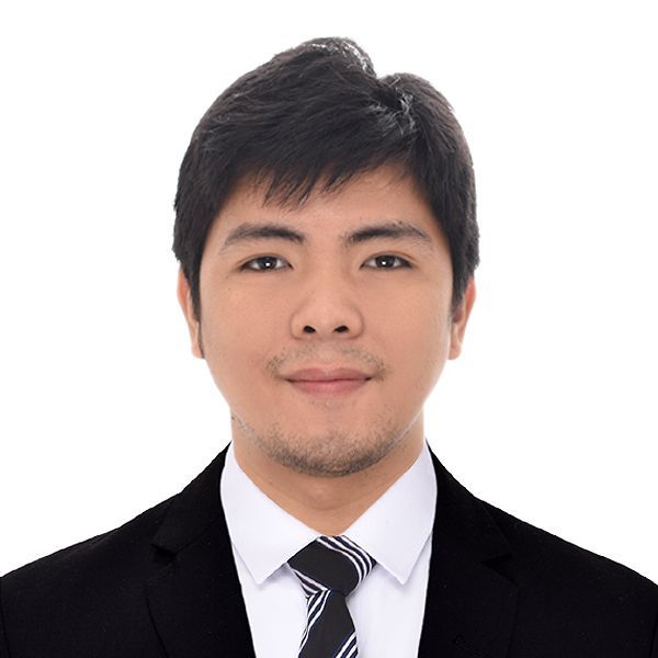 A man in a maroon shirt is sitting at a table with a plate of food.