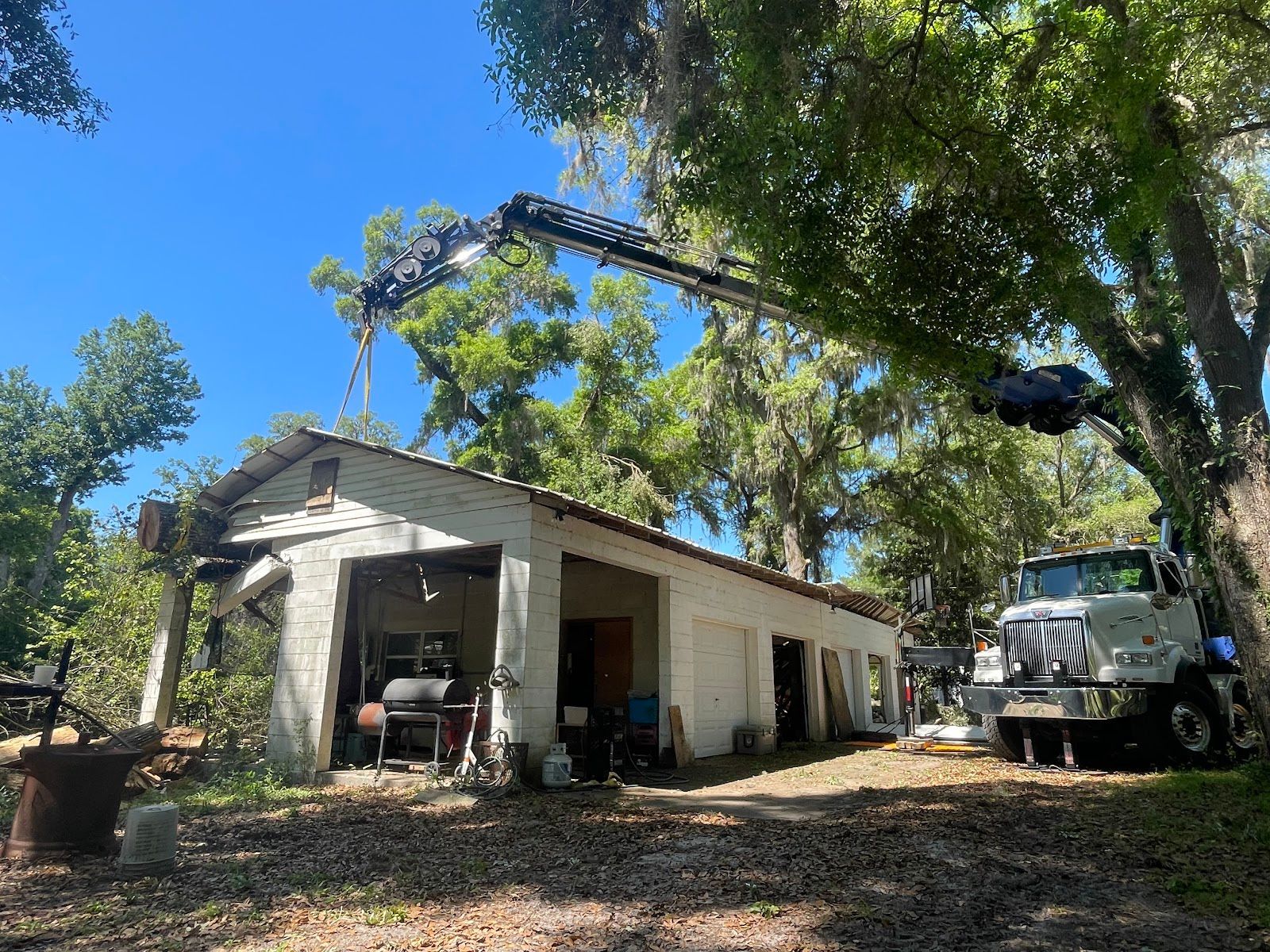 A truck is parked in front of a garage with a crane attached to it.